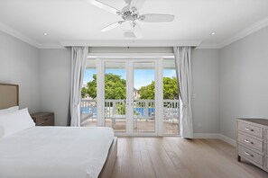 A bedroom with a bed, a dresser, a ceiling fan, and a sliding glass door leading to a balcony. - Spacious 4-bedroom townhome in peaceful Palm Cay,  New Providenc, Nassau. (New Providence)