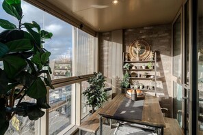 A modern kitchen with a wooden table, a built-in shelf with plants, and a large window overlooking the city. - Lovely 1-bedroom apartment in London perfect for your city stay (London)