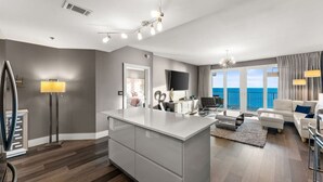 Een moderne woonkamer met een groot eiland, een flatscreen televisie en uitzicht op de oceaan.
