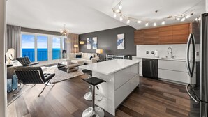 Een moderne keuken met een centraal eiland, een eetgedeelte met uitzicht en een woonkamer met een bank en stoelen.
