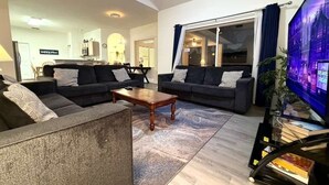 A modern living room with two sofas, a coffee table, and a television. - 5BR Disney Retreat | Private Pool, Spa & Game Room — Sleeps 14 (Kissimmee)