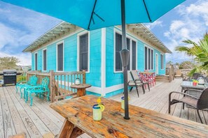 A turquoise house with a wooden deck, outdoor furniture, and a large umbrella. - Adorable 1-bedroom house w/private entrance, beach 2 blks in charming Galveston (Galveston)