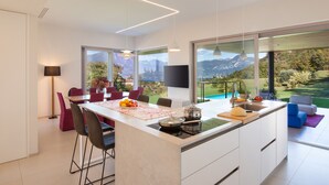 Een moderne keuken met een groot eiland, een eethoek en uitzicht op bergen.