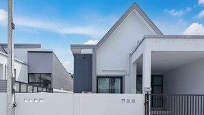 Una casa moderna de dos pisos con fachada blanca y techo negro.