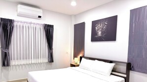 Una habitación de hotel moderna con una cama grande, un aire acondicionado de pared y dos cuadros enmarcados.