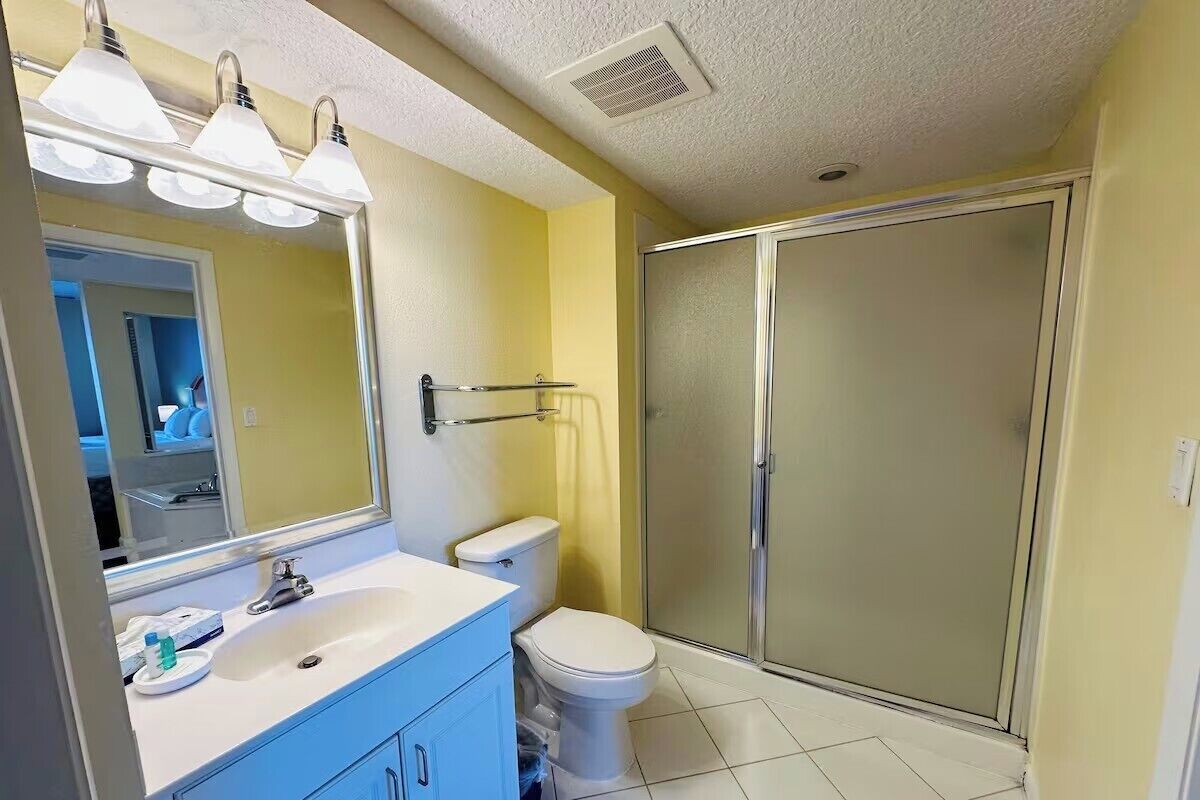 A bathroom with a sink, mirror, toilet, and shower.