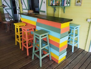 A bar area with a colorful stool arrangement and a shelf with bottles.
