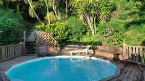 Eine Holzterrasse umgibt einen rechteckigen Pool, umgeben von einem Holzzaun und einer Bank.