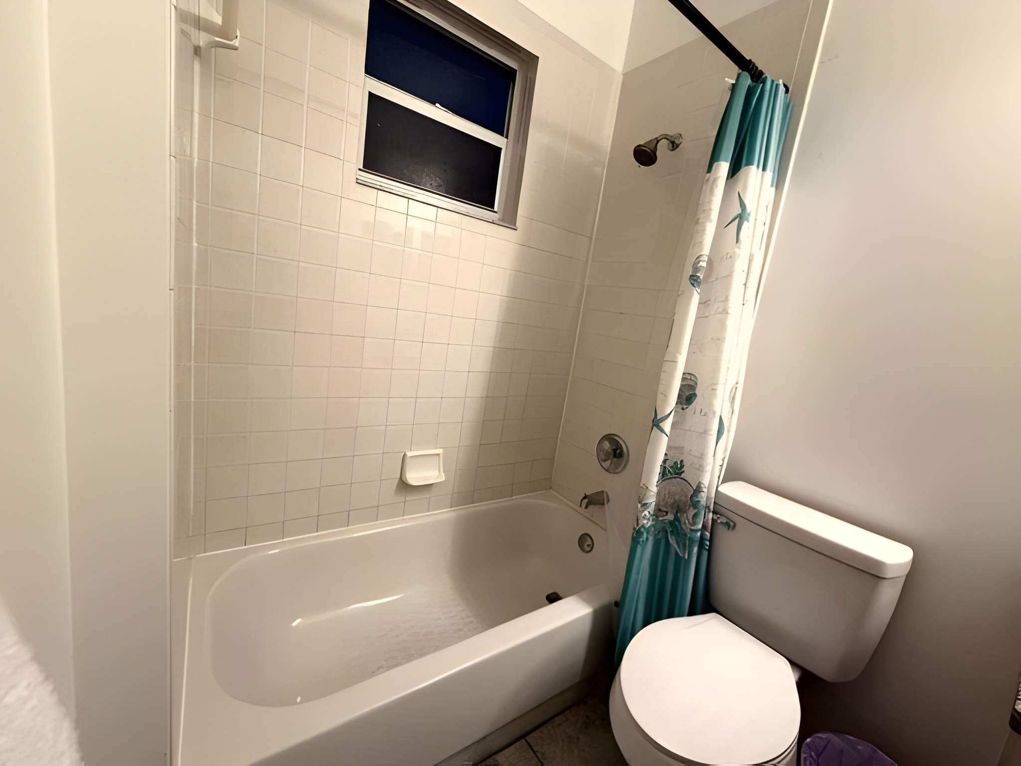 Un baño con bañera, inodoro y cortina de ducha.