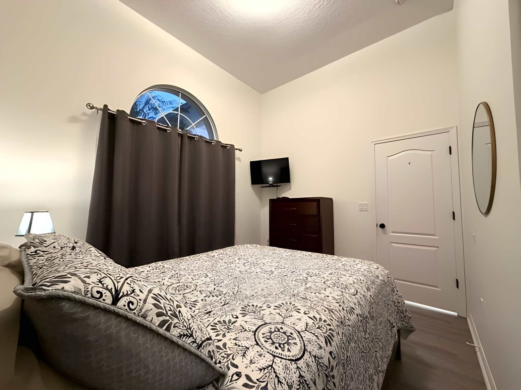A bedroom with a bed, a TV, a wardrobe, and a door.