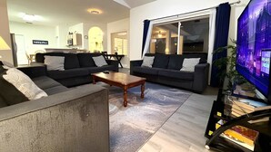 Una sala de estar moderna con dos sofás, una mesa de centro y un televisor de pantalla plana.