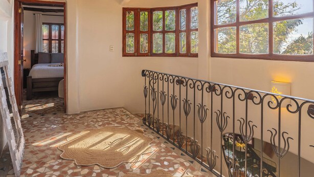 Een hal met een patroon vloer, een bed op de achtergrond en een balustrade met decoratieve details.