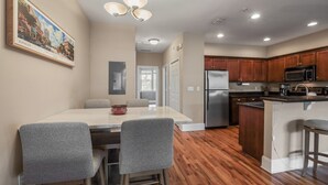 A modern kitchen with wooden cabinets, a stainless steel refrigerator, and a bar area.
