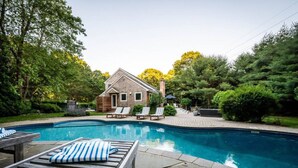 Ein Garten mit Swimmingpool, Liegestühlen und einem Holzhaus.