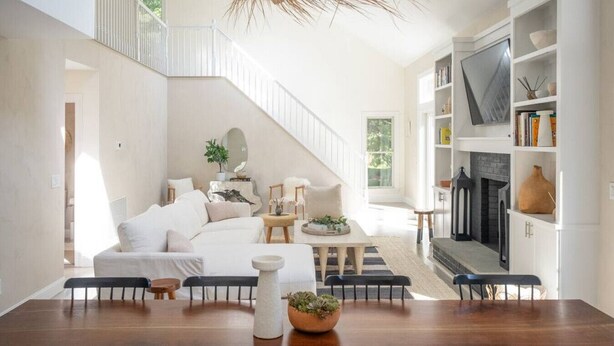 Ein geräumiges Wohnzimmer mit hoher Decke, Kamin und einer Treppe, die in einen oberen Bereich führt.