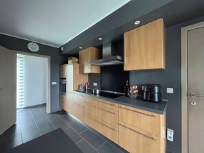 A modern kitchen with wooden cabinets, a stainless steel range hood, and a black countertop. - Enjoyable 3-bedroom house with Saun in Belgian Ardenne for your getaway (Fauvillers)
