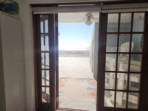 A doorway leading to a tiled outdoor area with a ceiling fan above. - Step out the door with toes in the sand and a drink in your hand! (Indian Shores)