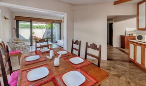 A dining area with a wooden table set for six, surrounded by wooden chairs. - Spacious 7-bedroom villa in fabulous Pointe d'Esny (Pointe d'Esny)