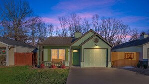 A single-story house with a green front door, a garage, and a small porch with a bench.