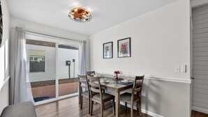 A dining area with a table set for four, chairs, a bench, and a ceiling light fixture.