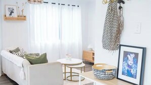 Un salon moderne avec un canapé, une table basse ronde et une petite table d’appoint.