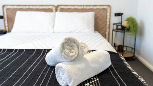 Un lit bien fait, avec des draps blancs et une couvre-lit rayée de noir et de blanc.