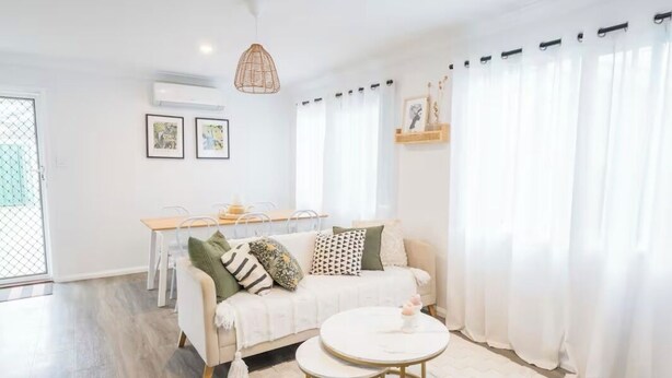Un salon moderne comprenant un canapé, une table basse ronde et un coin repas avec une table et des chaises.