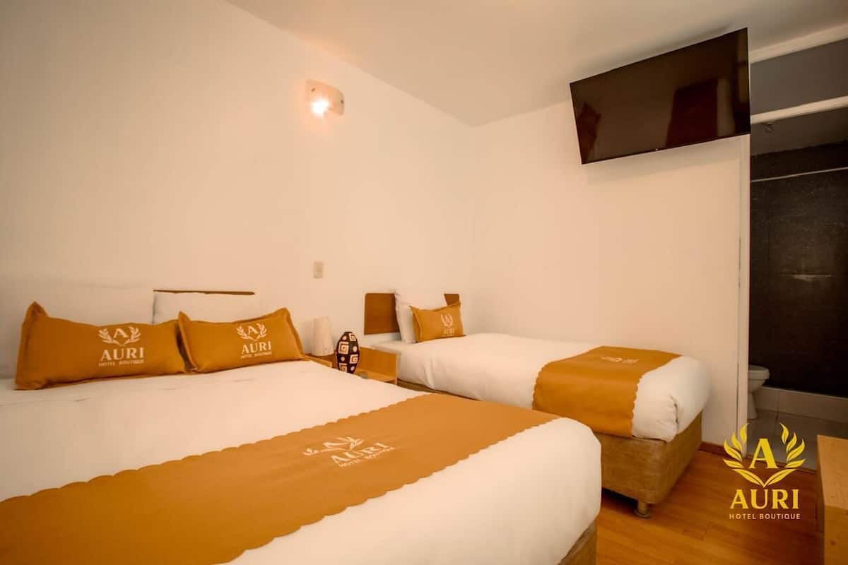 A hotel room with two beds, each with matching pillows and a central light fixture.