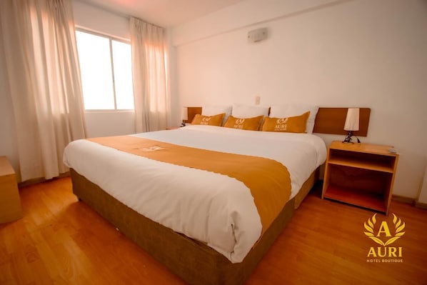 Une chambre d’hôtel avec un grand lit, une table de chevet et une fenêtre avec des rideaux.