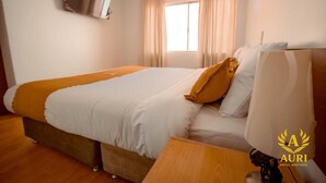 A hotel room with a bed, a TV mounted on the wall, and a window with curtains. - AURI HOTEL BOUTIQUE (Cusco)