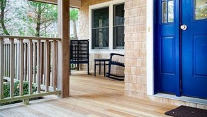 Une véranda en bois avec une porte bleue, un banc et une table.