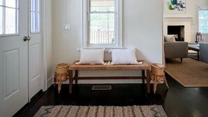Un couloir avec un banc, une cheminée et une vue sur le salon.