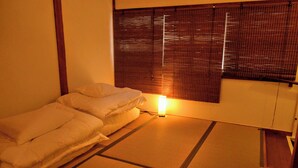 A room with a bed, a bedside table, a lamp, and a window with blinds. - Namba 13 min｜6 min walk from station｜Wi-Fi｜Nintendo Switch｜48 m2 private house｜10 min walk from Tsutenkaku (大阪市)