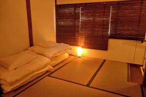 A room with a bed, a bedside table, a lamp, and a window with blinds. - Namba 13 min｜6 min walk from station｜Wi-Fi｜Nintendo Switch｜48 m2 private house｜10 min walk from Tsutenkaku (大阪市)