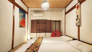A hotel room with a wooden ceiling, a large bed with a decorative bed runner, a red umbrella, and traditional Japanese artwork on the walls. - Namba 13 min｜6 min walk from station｜Wi-Fi｜Nintendo Switch｜48 m2 private house｜10 min walk from Tsutenkaku (大阪市)