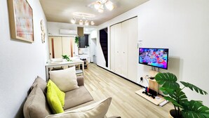 A modern living room with a sofa, a TV, and a ceiling fan. - Namba 13 min｜6 min walk from station｜Wi-Fi｜Nintendo Switch｜48 m2 private house｜10 min walk from Tsutenkaku (大阪市)