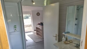 Une salle de bain avec un lavabo blanc, un miroir et une douche.