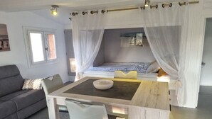 Une chambre à coucher avec un lit à baldaquin, une table de chevet, une chaise et une fenêtre.