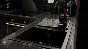 Cuina moderna amb un rentaplat de superfície inoxidable, una campana extractora i un salvassecs amb un disseny que recorda al marbre.