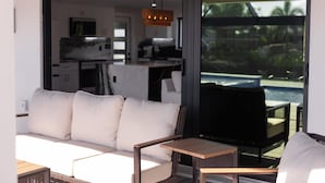 Ett modernt vardagsrum med en soffa, ett litet bord och utsikt över en pool genom en glasdörr.