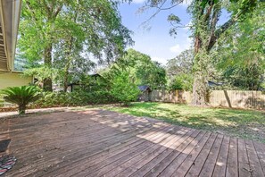 Un jardin avec une terrasse en bois, un petit potager et une clôture en bois.
