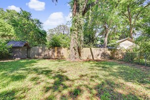 A backyard with a wooden fence, a shed, and a tree. - The Branches - Adorable 2 Bedroom Midtown Bungalow (Tallahassee)