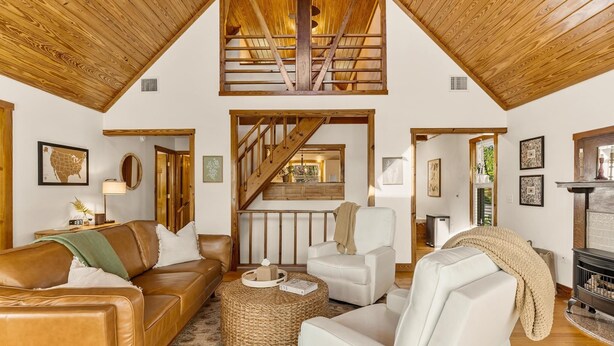 A spacious living room with a high ceiling, wooden beams, a staircase, and a fireplace. - Langoon Lodge 4-BR 3-BA, 8 beds. Walk to DT&Lake (Mount Dora)