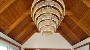 A wooden dining table with wicker chairs, a hanging light fixture, and a potted plant in the center. - Langoon Lodge 4-BR 3-BA, 8 beds. Walk to DT&Lake (Mount Dora)