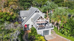 A modern two-story house with a large balcony, surrounded by lush greenery and a well-maintained garden. - Langoon Lodge 4-BR 3-BA, 8 beds. Walk to DT&Lake (Mount Dora)