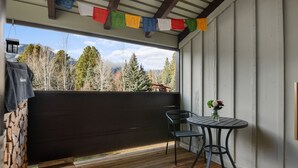 A covered outdoor area with a wooden deck, a table with chairs, and a view of mountains. - RMR: Alpine Fir 722 Condo in The Aspens/Wilson, WY (Wilson)