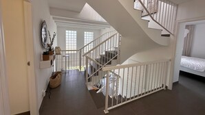 Ein geräumiger Flur mit einer weißen Treppe, die zu einem Schlafzimmer führt.