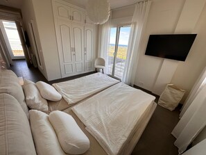 A bedroom with two beds, a TV, and a view of the desert through the window. - A cozy villa overlooking Denia with views of the mountains and the sea. Animals ❤️ (Pedreguer)