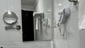 A modern bathroom with a white sink, a round mirror, a hairdryer, and a towel rack. - The High View (Al Baha)