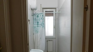 Une petite salle de bain avec deux toilettes, un lavabo et un espace douche.